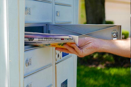 Person's hand pulling mail out of a mailbox 